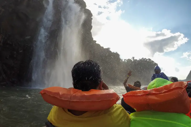 Passengers in life jackets in the spray directly under the falls
