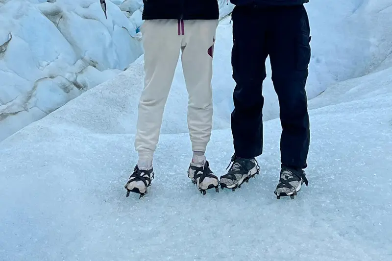 Two people in crampons standing on the ice of the glacier