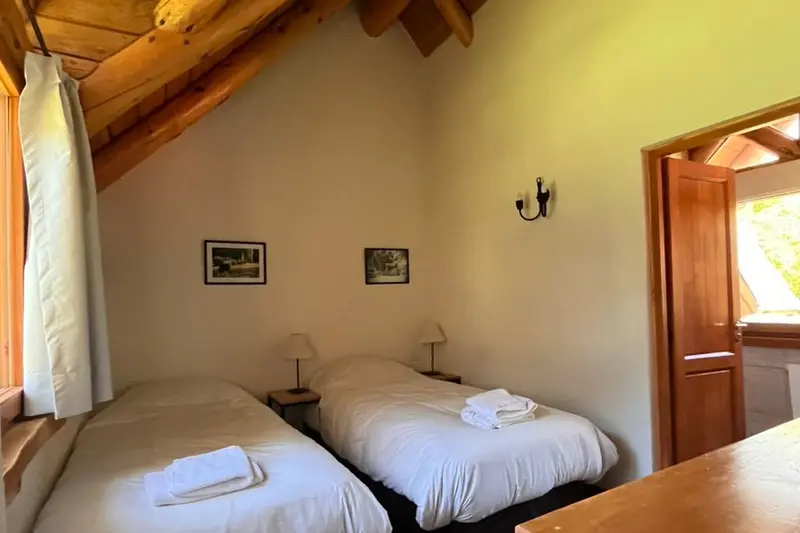A bedroom with two single beds under a wooden beamed ceiling