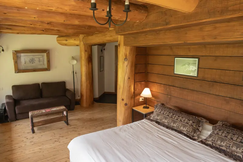A room with wooden walls, a sofa and a bed