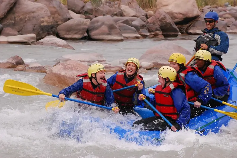 Rafters in helmets and life jackets paddling through white water