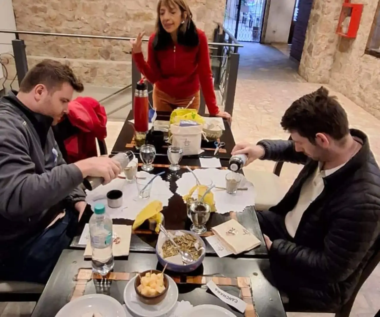 People around a table with mate gourds and thermos flasks