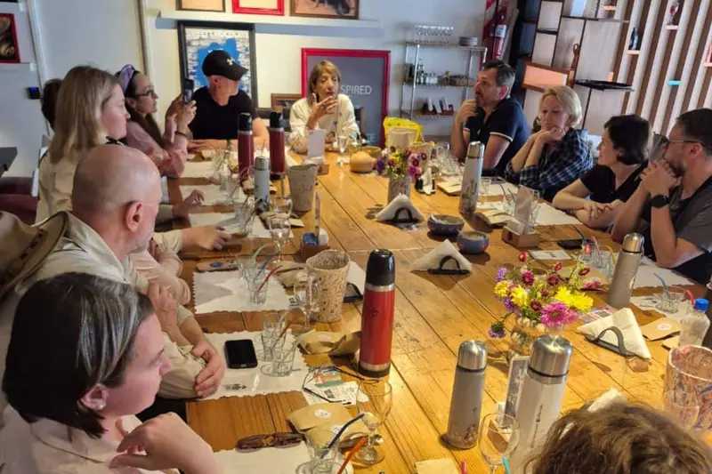 A group around a long table with thermoses and mate cups