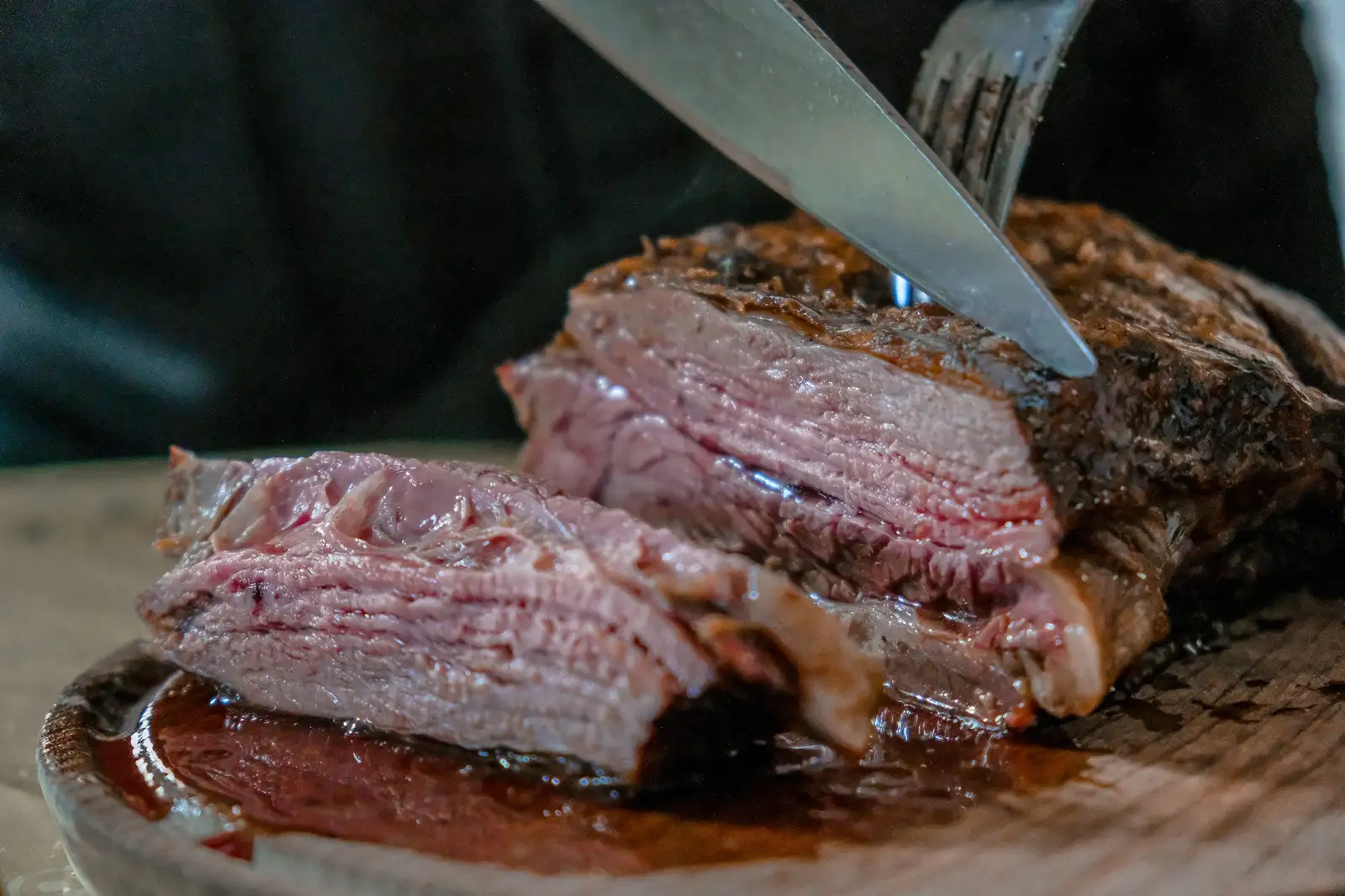 A knife cutting into a thick cut of beef