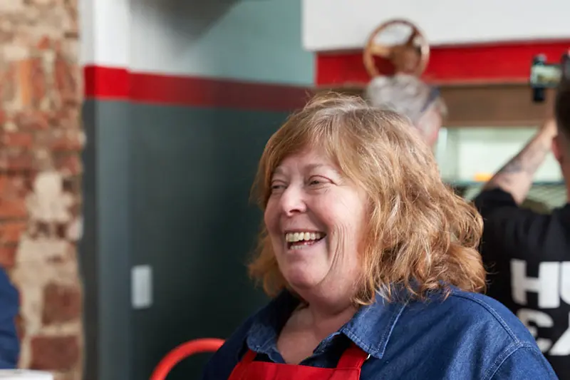 Betty holding a plate of chimichurri toast, laughing
