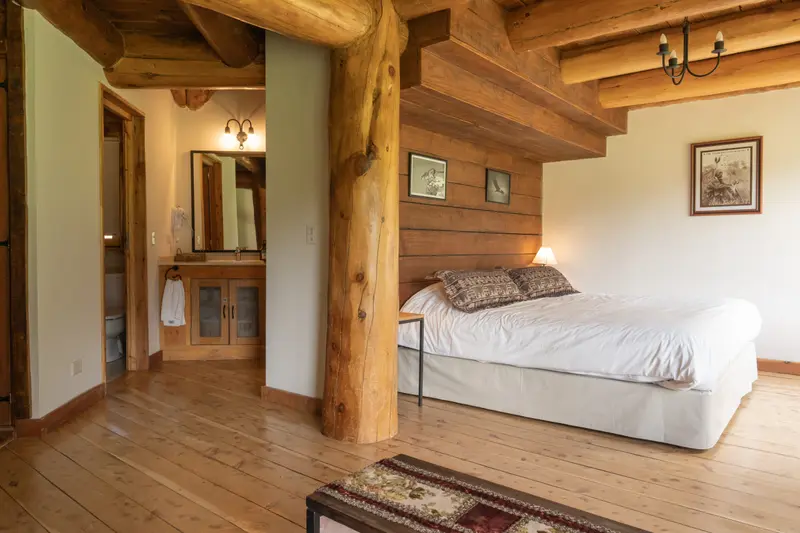 A room with wooden posts, a bed and a mirror