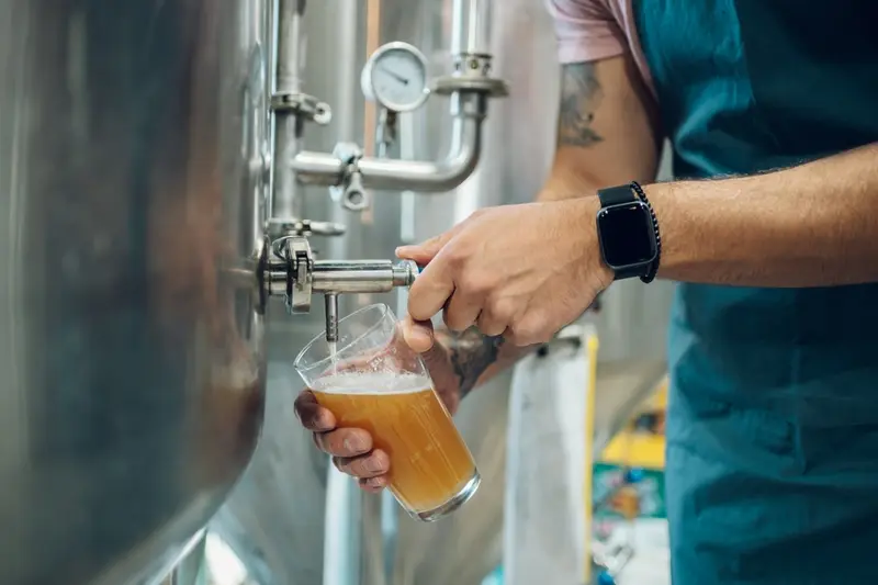 A hand filling a glass from a tap at the brewery