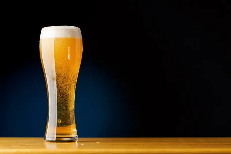 A tall glass of beer with a head on it
