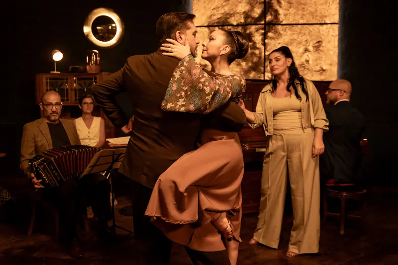 A tango couple dancing, with the musicians behind them