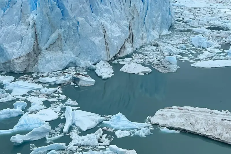 The glacier front with broken ice floating in the water below it