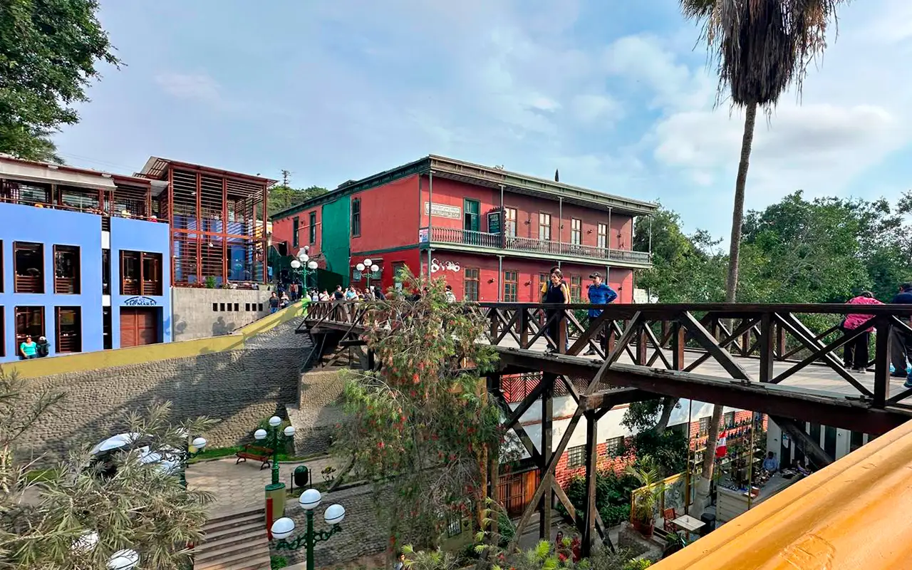 A painted building beside a footbridge, with palms above the street