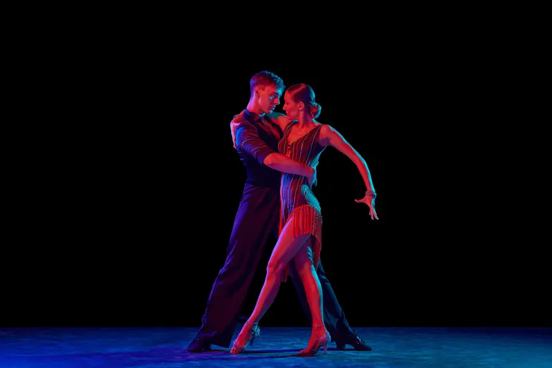 A tango couple lit in red and blue on a dark stage
