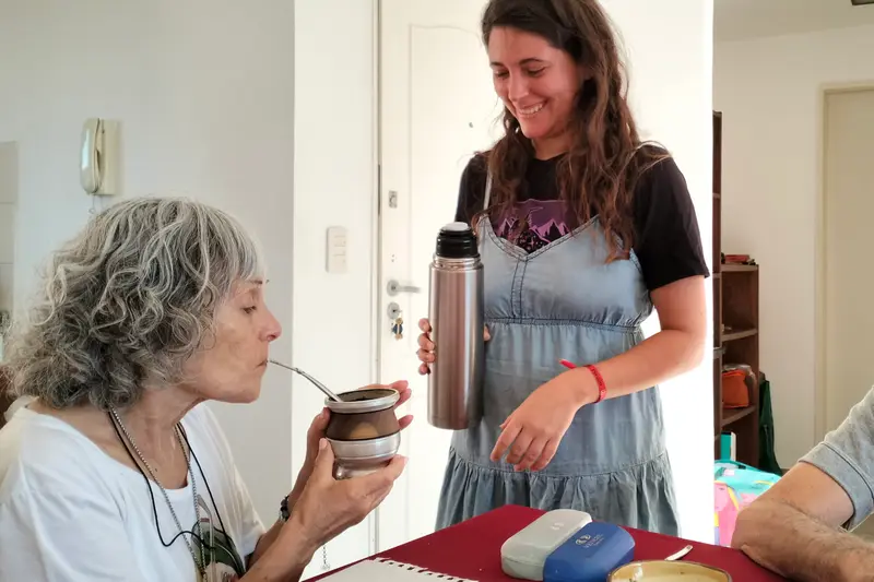 Two women sharing mate, one holding the thermos