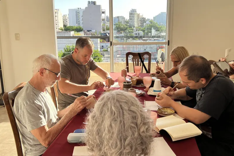 A group around a table painting, with mate cups in front of them