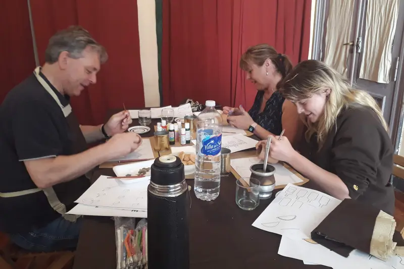 People at a table working on their mate cups with brushes