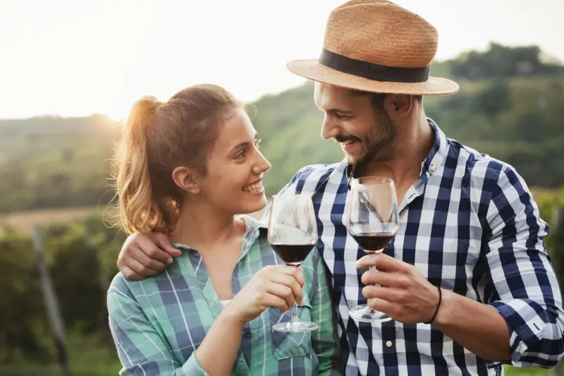 A couple raising glasses of red wine outdoors