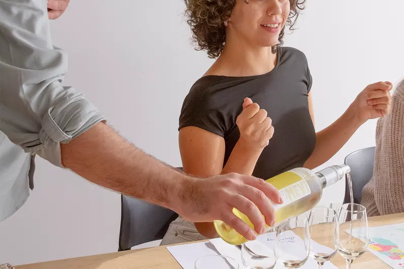A host pouring white wine at a tasting table
