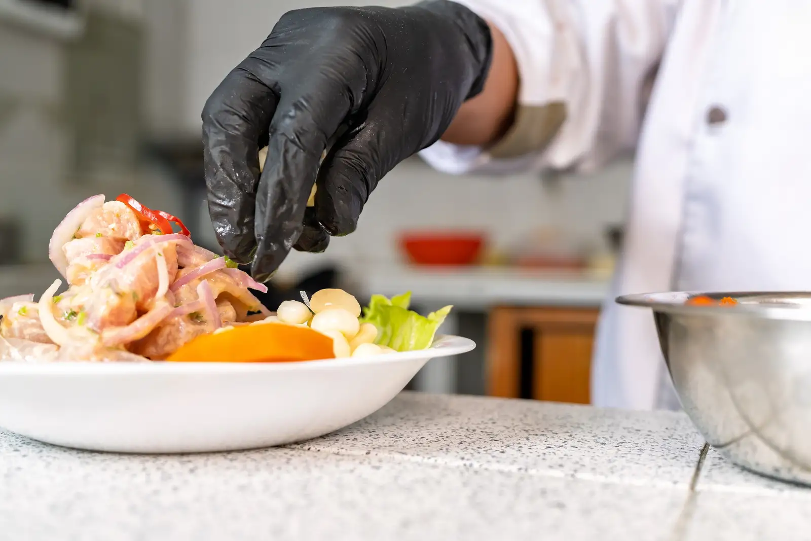 Chef adding final touch of cilantro to a plate of peruvian ceviche, a traditional seafood dish