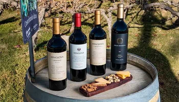 Four bottles on a barrel head, with a board of nuts beside them