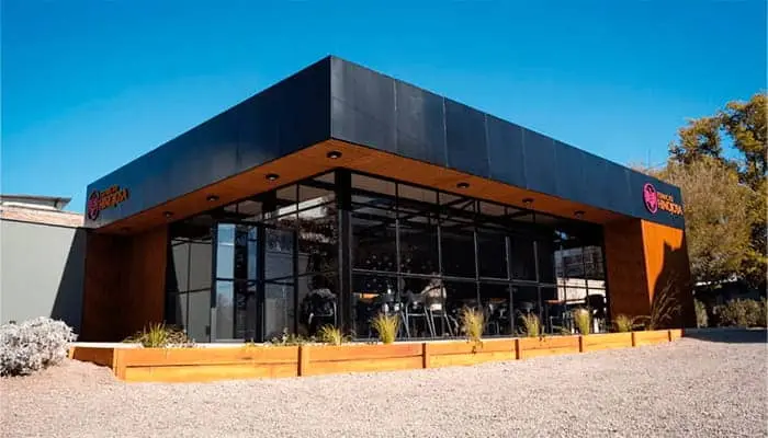 A dark modern winery building at the end of a gravel drive