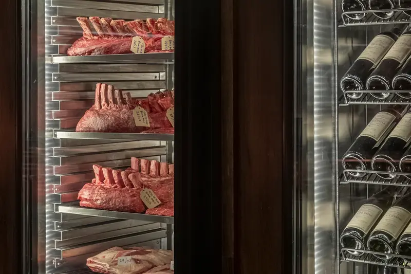 Racks of beef dry-aging in a glass cabinet