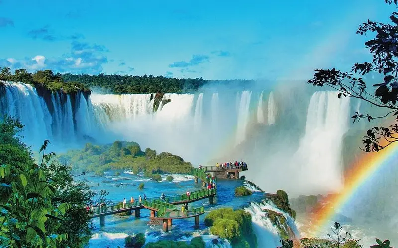 The falls with a rainbow over them and the walkways below