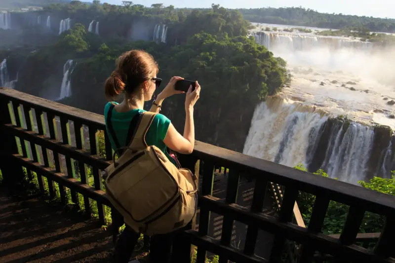 A visitor photographing the falls from a wooden walkway
