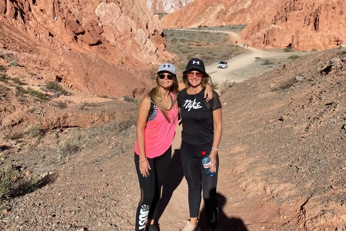 Two visitors on a dirt road between red hills