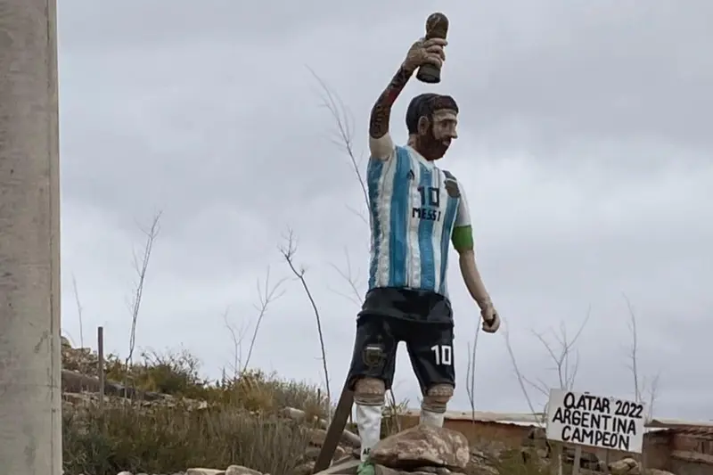 A statue of Messi holding a trophy, above the valley