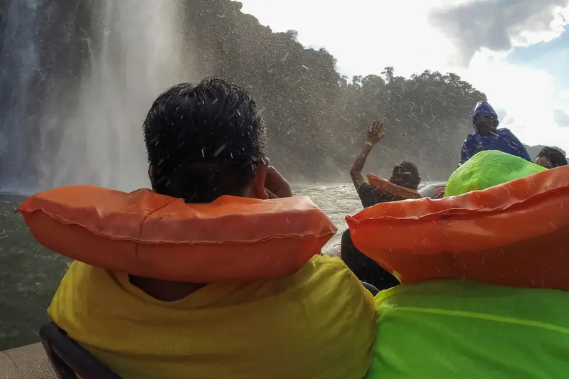 Passengers in orange life jackets in the spray under the falls