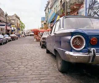 A vintage blue car parked on a cobbled street in La Boca