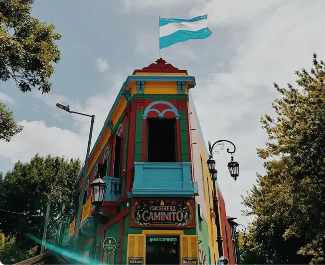 A painted building on Caminito, with the street sign below it
