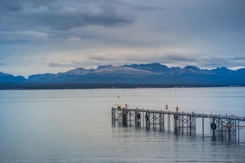 A wooden jetty on a still lake, with mountains behind
