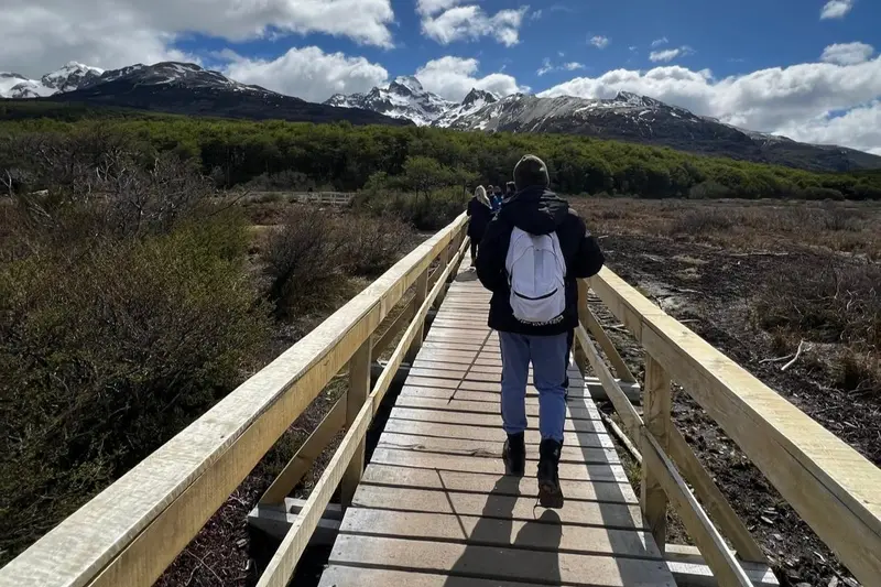 A walker on a boardwalk heading towards the mountains