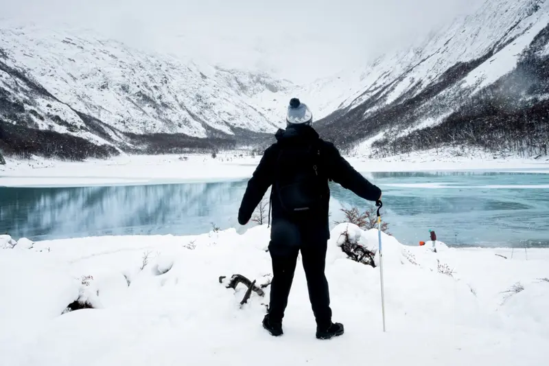A walker in the snow beside a frozen lake