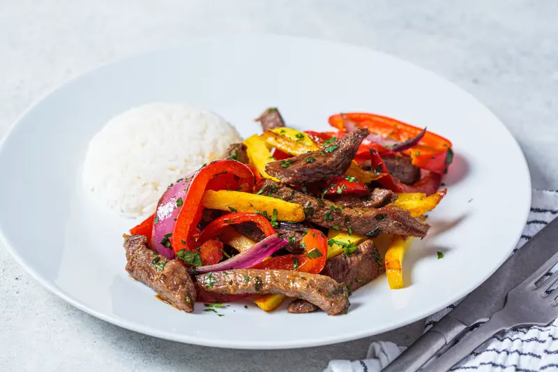 Lomo saltado with rice on a white plate