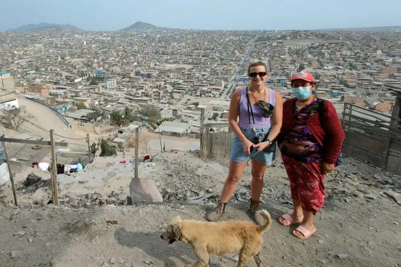 Two people on a dusty hillside above the city, with a dog beside them