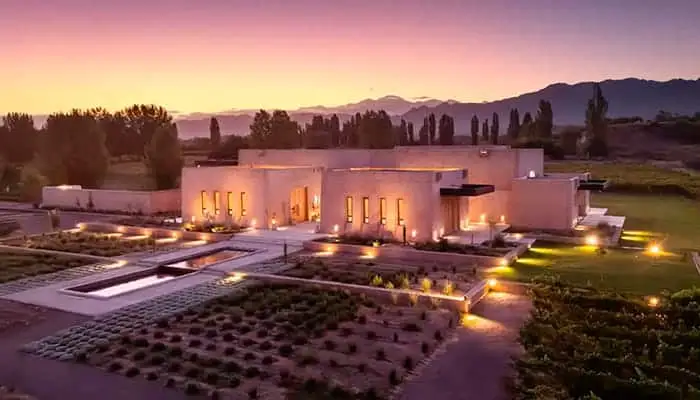 A low winery lit at dusk, with the mountains behind it