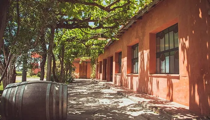 A red-walled winery courtyard under a pergola