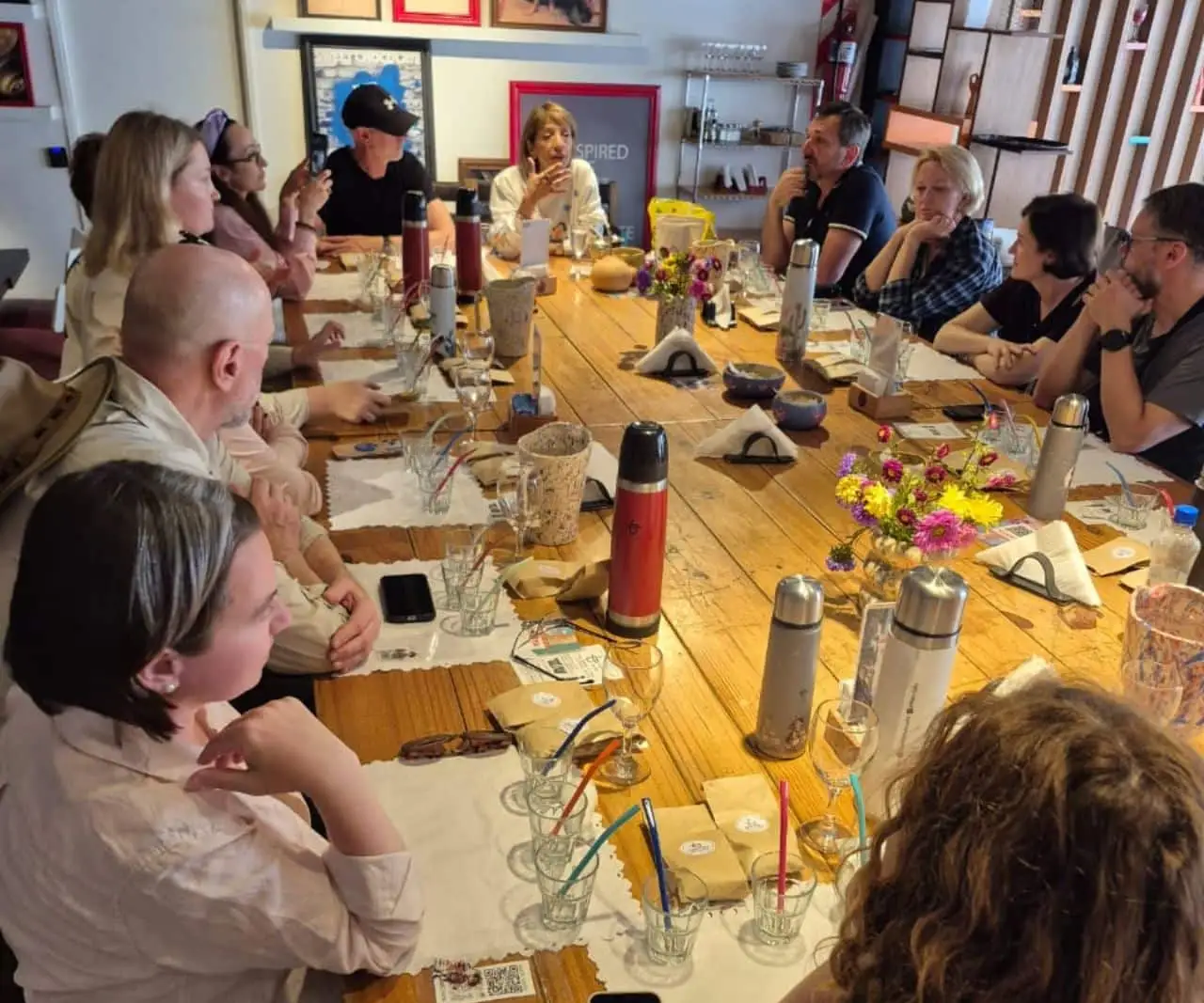 A long table of guests with thermos flasks and mates