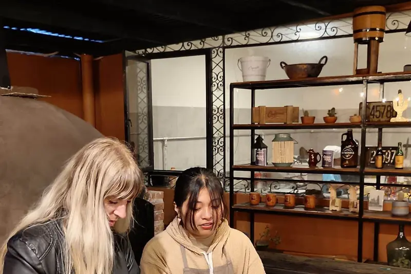 Two people at a counter, with shelves of jars behind them