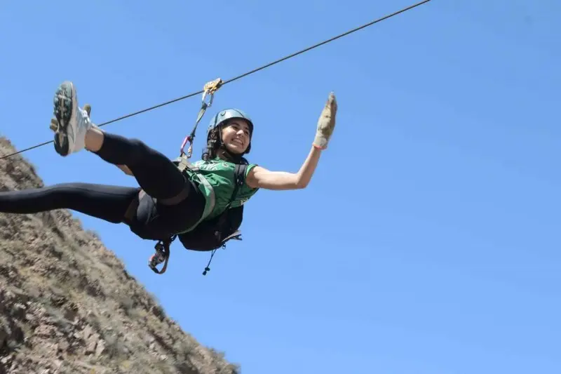 A person on a zip line against the sky