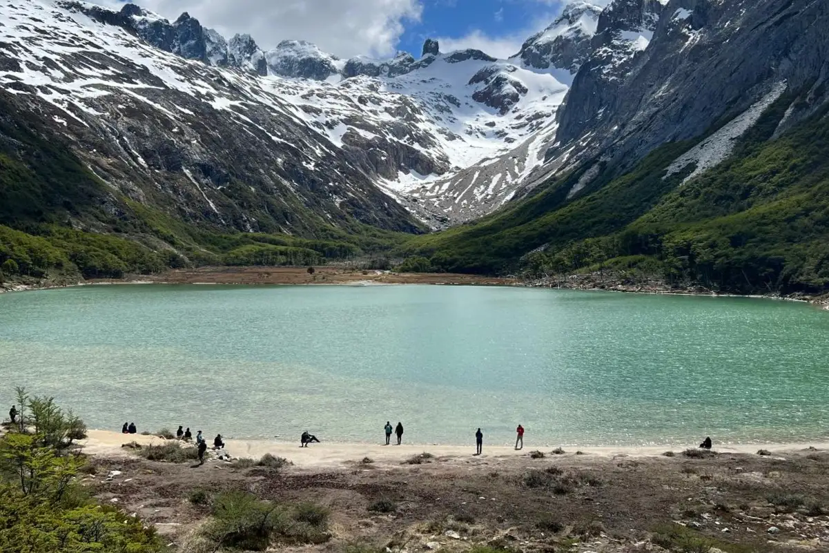 A bay in the national park, with the snow range behind and people on the shore