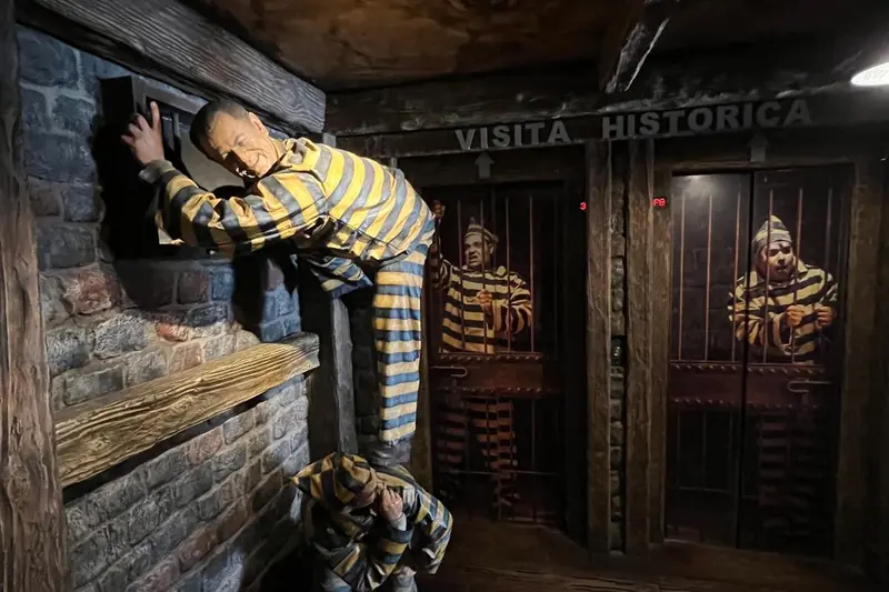 A child looking into a cell display with figures in striped prison uniforms