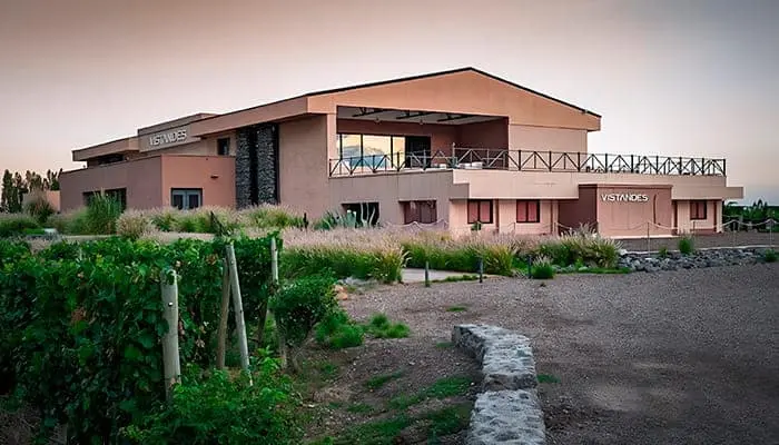 A winery building with a pink facade and a covered terrace