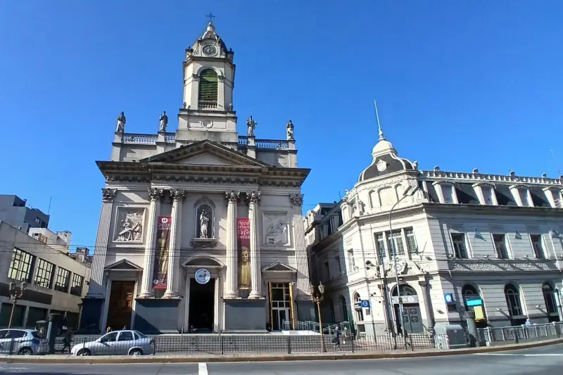 A church with a bell tower, between city buildings
