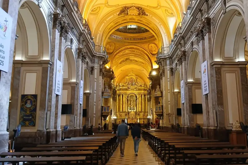 The inside of a basilica, looking down the nave to a gilded altar