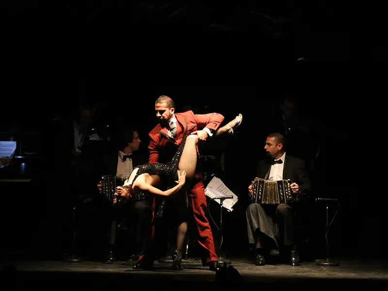 A tango couple on stage, with the bandoneon player beside them