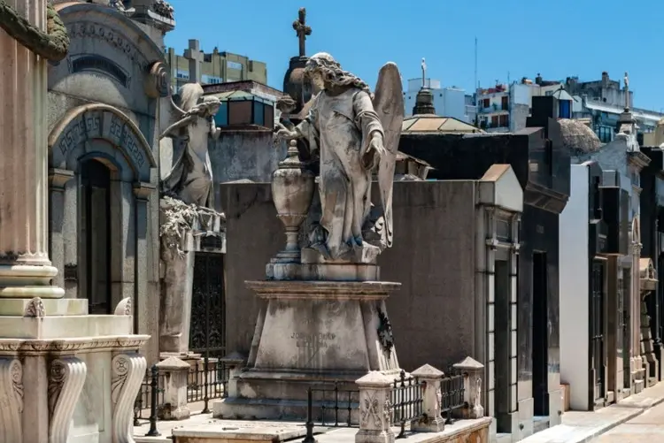 Mausoleums with stone statues along a path in the cemetery