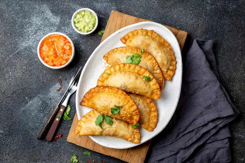 Fried empanadas on a plate with two dips
